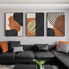 three abstract paintings hang on the wall above a black couch and coffee table in a modern living room