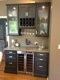 a kitchen with stainless steel appliances and wine glasses on the cabinet doors, along with hardwood flooring