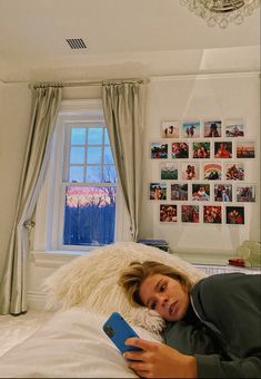 a woman laying on top of a bed next to a window with pictures on the wall