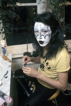 a man with his face painted like a clown sitting in front of a sink and looking at the camera