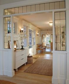 an open door leading into a living room with white furniture and wood floors on either side