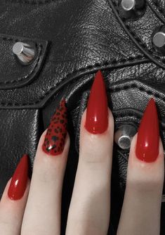 a woman's hand with red nail polish and leopard print on it