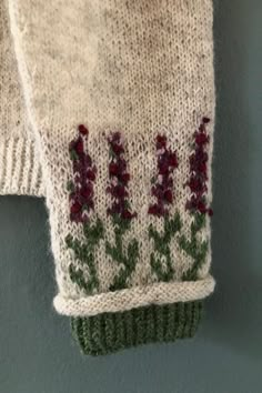 a pair of white gloves with red flowers on them hanging from the side of a wall