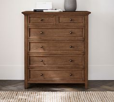 a wooden dresser sitting on top of a rug next to a white wall and floor