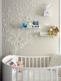 a white crib with stuffed animals and a tree on the wall