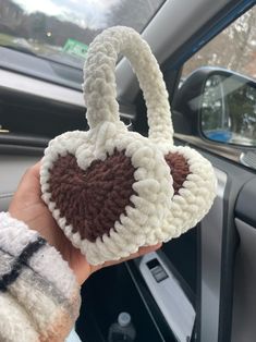 someone is holding up a crocheted bag in their hand while inside the car