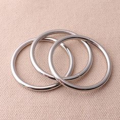 three silver rings sitting on top of a beige cloth covered floor next to each other