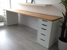 a white desk with four drawers and a potted plant