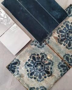 an old tile floor with blue and white designs on it, next to a piece of paper