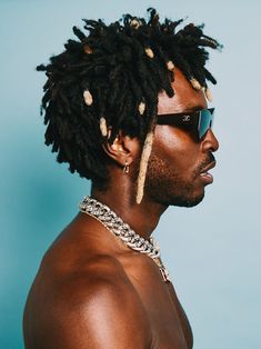 a man with dreadlocks and sunglasses on his head wearing a chain around his neck