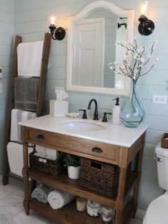 a white toilet sitting next to a bathroom sink under a mirror and a wooden ladder