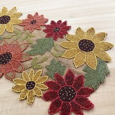 several different colored flowers on a white table cloth with sequins in the center