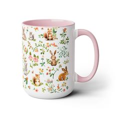 a pink and white coffee mug with animals on it's side, in front of a floral background