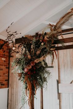 an arrangement of flowers and greenery is hanging from the ceiling