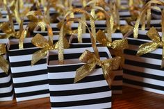 small black and white striped bags with gold bows on the top are sitting on a table