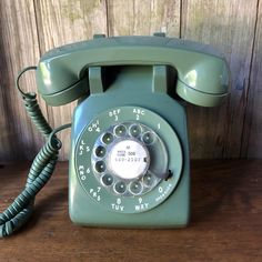 an old green phone sitting on top of a wooden table