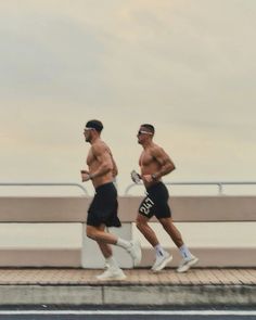 two men running on a bridge over water