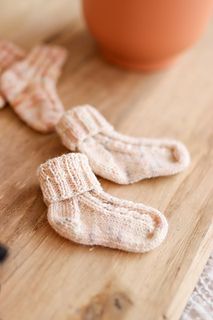 two pairs of socks sitting on top of a wooden table next to a potted plant