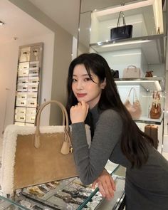 a woman standing in front of a display case holding a purse