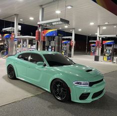 a mint green dodge charger parked at a gas station