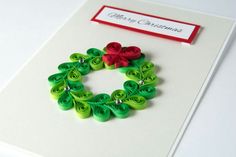 a christmas card with a green wreath and red bow on it, sitting on a table