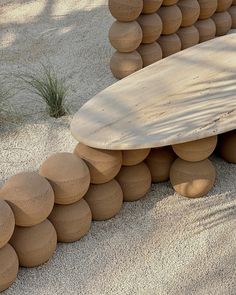 a wooden surfboard sitting on top of a pile of balls in the sand next to a tree