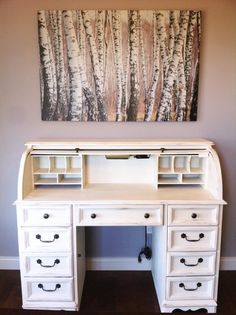 a white desk with drawers underneath a painting