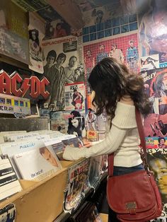 a woman standing in front of a record store counter with records on the wall behind her