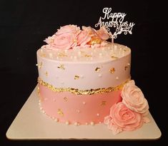 a pink and gold birthday cake with flowers on top