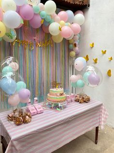 a table topped with a cake and balloons