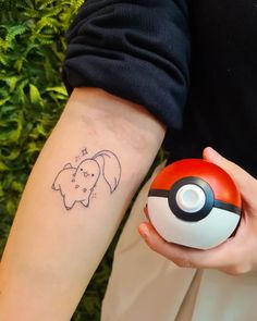 a person with a tattoo on their arm holding a pokemon ball