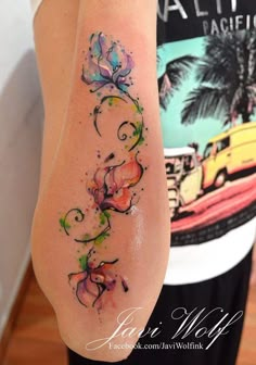 a woman's leg with watercolor tattoos on it