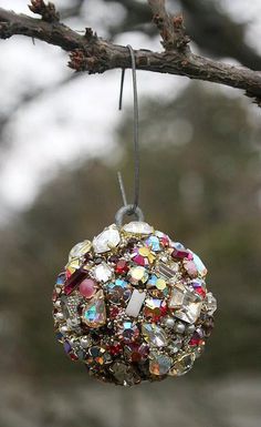 an ornament hanging from a tree branch with lots of beads and stones on it