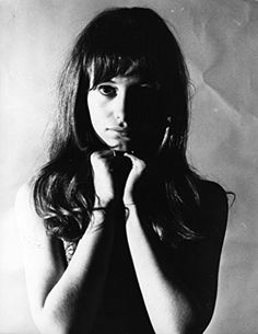 a black and white photo of a woman with her hands on her chest, looking at the camera