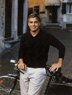 a man standing next to his bike in the street