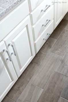 a kitchen with white cabinets and gray flooring