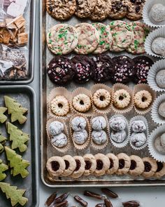 an assortment of cookies and pastries in trays next to christmas tree shaped cookies