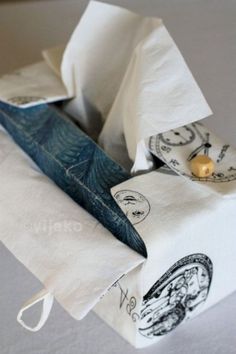 folded napkins with designs on them sitting on top of a white tablecloth covered surface