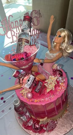 a barbie doll sitting on top of a cake with pink icing and sprinkles