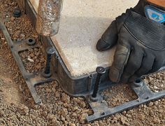 a pair of work gloves sitting on top of a piece of metal in the dirt