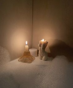 two candles sitting on top of snow next to each other