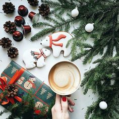 a woman holding a cup of coffee next to christmas decorations