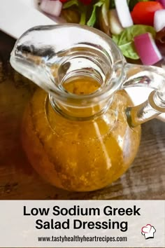 a jar filled with salad dressing sitting on top of a wooden table next to vegetables