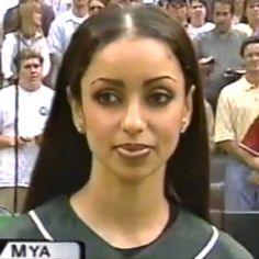 a woman with long black hair standing in front of a crowd at a baseball game