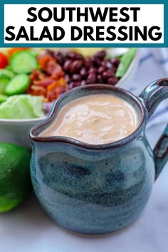 a blue pitcher filled with dressing next to a bowl of beans and lime wedges