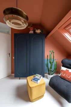 an orange and blue room with a yellow footstool in the corner next to a green plant