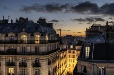 the sun is setting over an old building in paris, with many windows and balconies