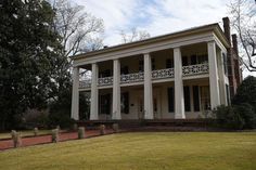 a large white house sitting on top of a lush green field