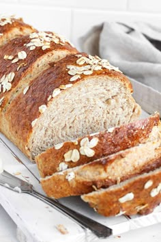 a loaf of bread sitting on top of a cutting board next to a knife and fork