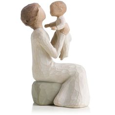 a ceramic figurine of a woman holding a baby sitting on a white surface